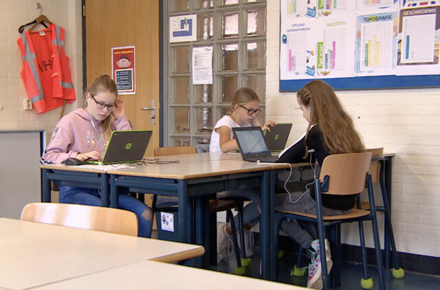 Meisjes in klaslokaal op laptops
