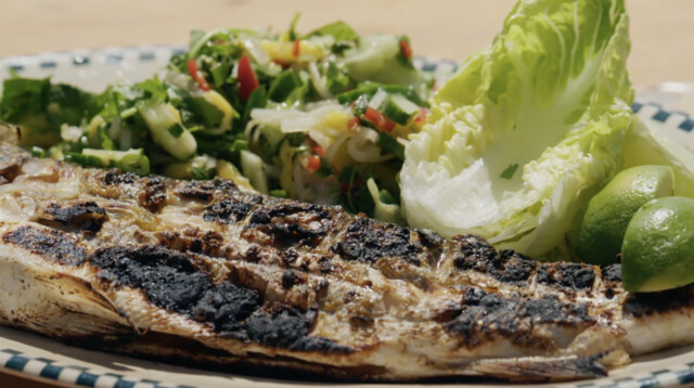 Verse zeebaars van de barbecue en geserveerd met een frisse en pittige salade.